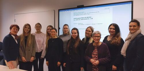 Gruppenfoto vor Beamer auf dem eine Worddatei mit dem Titel "Einführungsworkshop für Mentees"