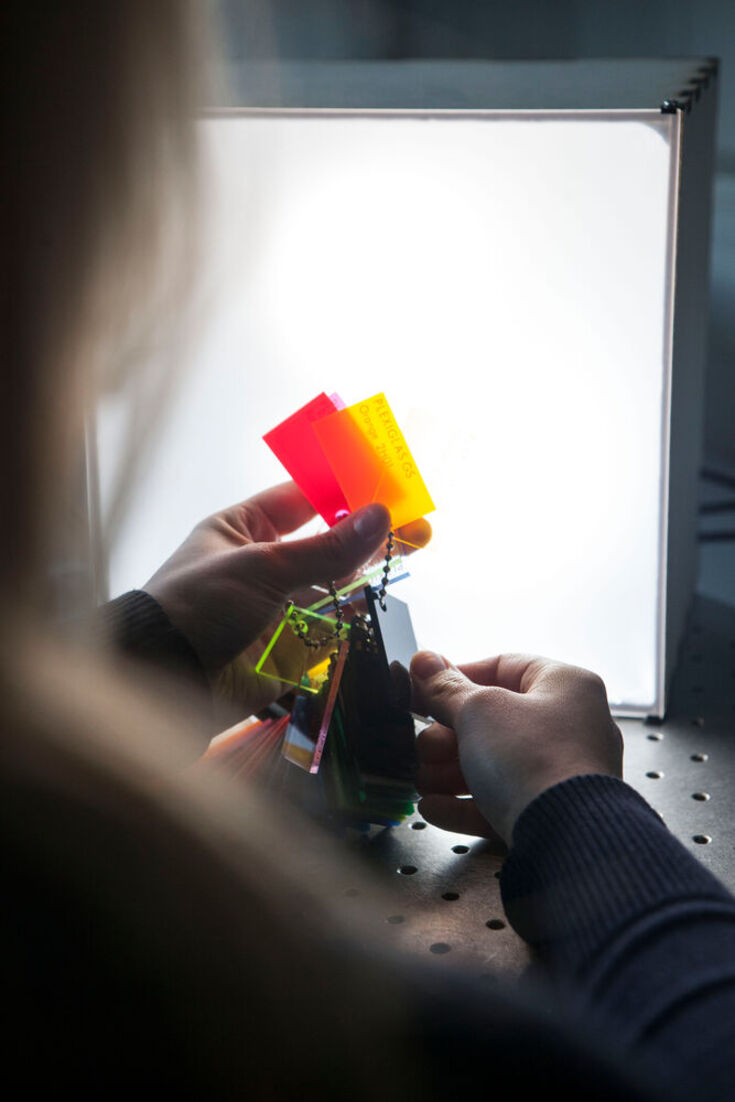 A student is experimenting with colourful plates in front of a light source.