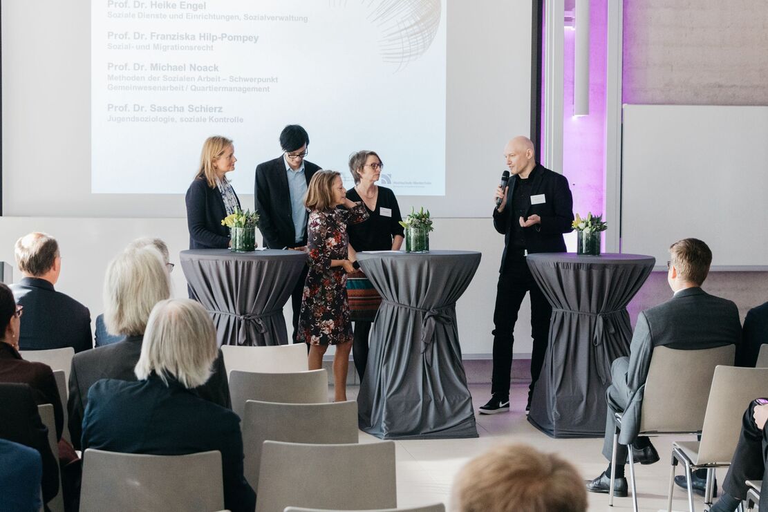 Menschen auf Bühne mit Stehtischen