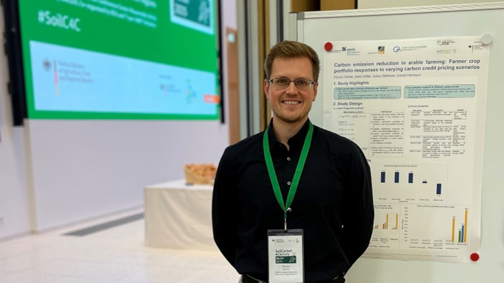 Florian Grebe in front of a poster at the SoilCarbon4Climate conference.