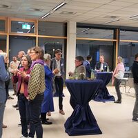 Get Together, Personen stehen um Stehtische herum, essen und unterhalten sich