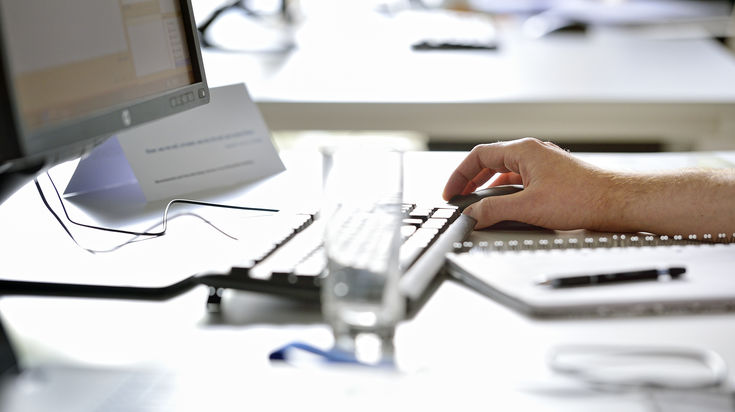 Screen with keyboard and one hand on the mouse