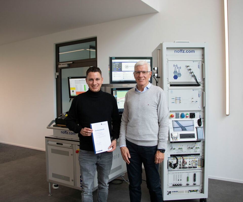 Zwei Männer mit Dankesurkunde vor einer Maschine