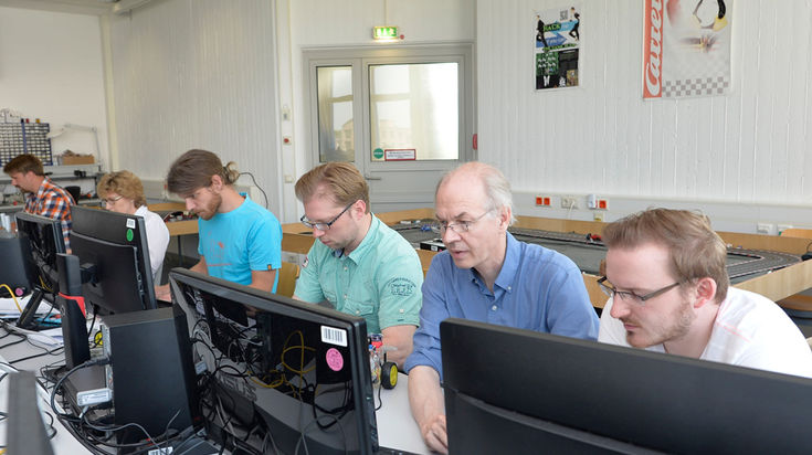 Five people sit at computers