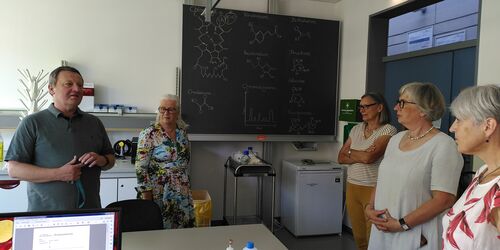 Chemielabor indem vier Frauen einem Mann zuhören