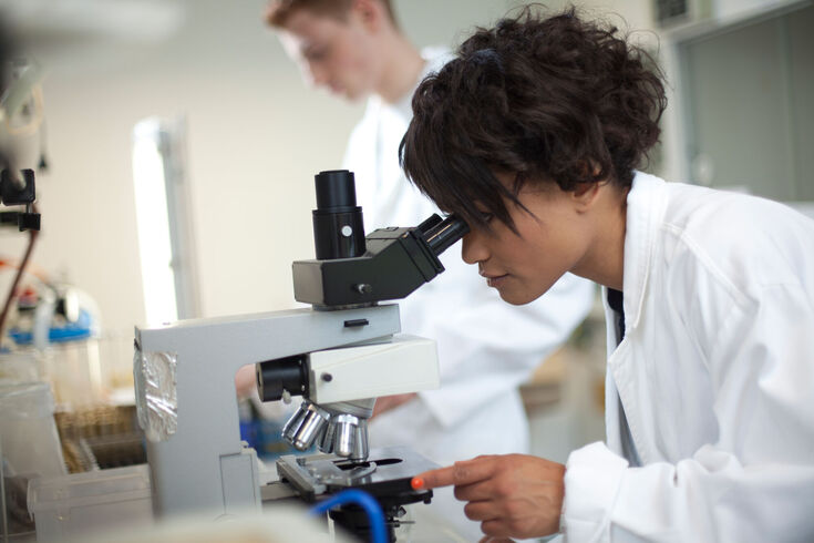 Chemistry student in front of a microscope.