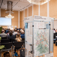 Depiction of the inner hall of the event. People looking ahead.